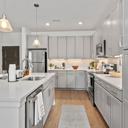 Beautiful kitchens with designer finishes large kitchen with island and white cupboards at Velo Riverside Apartments in Dayton, KY