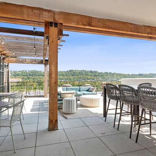 Everything within reach an outdoor patio with seating and a covering at Velo Riverside Apartments in Dayton, KY